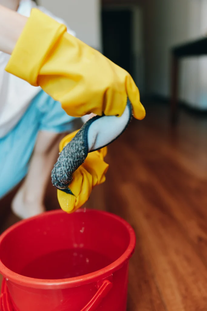 Uklízečka s červeným kbelíkem při mytí podlahy